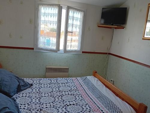 a bedroom with a bed and a tv and two windows at **Maison récente, proche plage, commerces et plan d'eau - L'Aiguillon-sur-Mer** - FR-1-194-275 in LʼAiguillon-sur-Mer