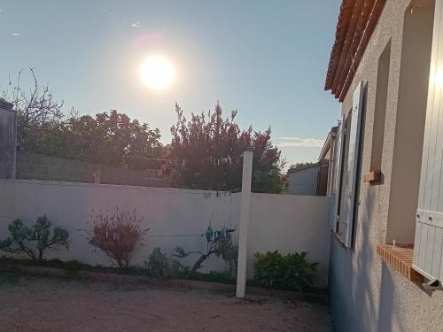 a white fence with the sun in the background at **Maison récente, proche plage, commerces et plan d'eau - L'Aiguillon-sur-Mer** - FR-1-194-275 in LʼAiguillon-sur-Mer