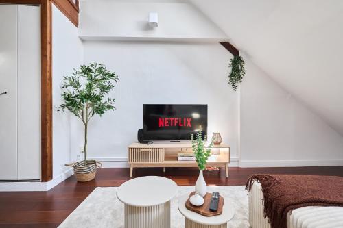 a living room with a tv on a white wall at Le Loft de la Porte de Mars - à 5 min de la gare in Reims