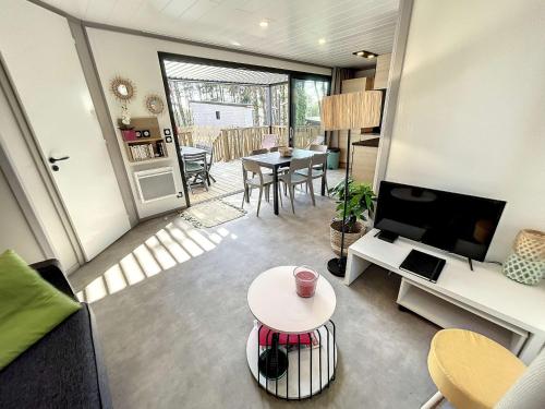 un salon avec un canapé, une télévision et une table dans l'établissement Chalet standing avec piscine chauffée, proche plage et commerces, équipé de WiFi - 6 couchages. - FR-1-361-513, à Jullouville