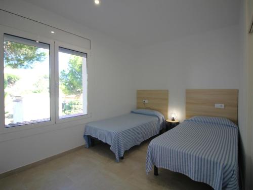 zwei Betten in einem Zimmer mit zwei Fenstern in der Unterkunft V. FANÉ ESQ - Casa con jardín y vista mar en Llançà acabada de reformar - ES-228-10 in Llança