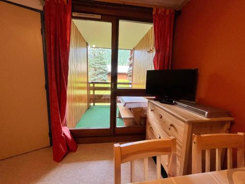 d'un salon avec une télévision et une porte coulissante en verre. dans l'établissement Studio cabine près navette, balcon exposé sud - FR-1-679-6, à Morzine