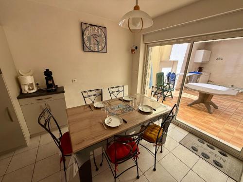 une table et des chaises dans une cuisine avec une horloge murale dans l'établissement Maison T3 avec cour close, proche plage et commerces, quartier Arago, Les Sables-d'Olonne - FR-1-92-657, à Les Sables-dʼOlonne