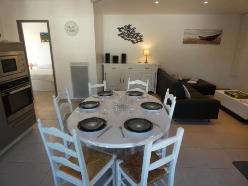 - une table à manger avec des chaises blanches dans le salon dans l'établissement Appartement moderne 68m² à Notre-Dame-de-Monts, 6 pers, accès PMR, terrasse, proche forêt et plages - FR-1-540-277, à Notre-Dame-de-Monts