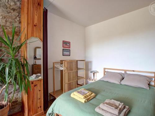 una camera da letto con un letto verde con sopra degli asciugamani di Appartement T2 avec terrasse, parking et wifi à St-Genest-Lerpt - FR-1-496-287 a Saint-Genest-Lerpt