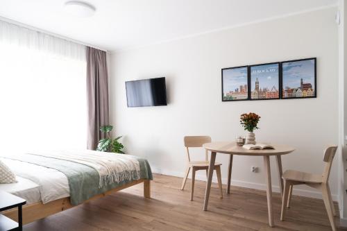 a bedroom with a bed and a table and a tv at Symphony City Square Aparthotel in Wrocław