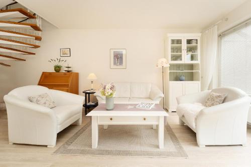 a living room with two white chairs and a coffee table at Waldstraße 2 Kellenhusenliebe in Kellenhusen