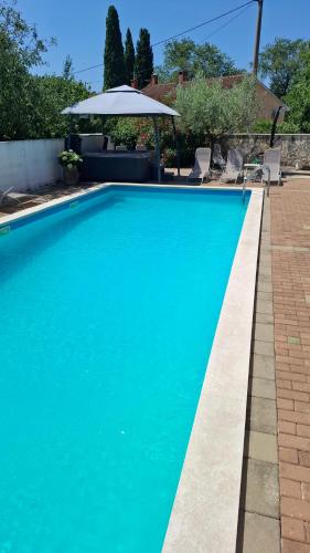 a blue swimming pool with chairs and an umbrella at Apartments Kimm II in Poreč