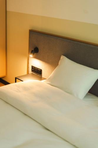 a bed with a white pillow and a lamp at Hotel Node 
