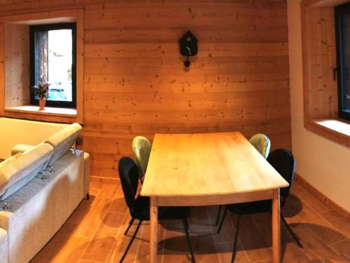 - une salle à manger avec une table en bois et un canapé dans l'établissement Charmant T3 avec Jardin, Parking, et Cuisine Équipée à Saint-Jean-d'Aulps - FR-1-573-130, à Saint-Jean-dʼAulps