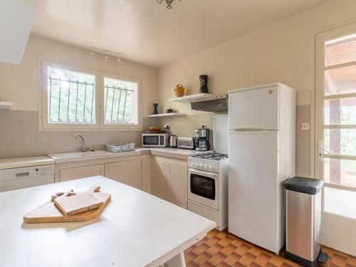 une cuisine avec un réfrigérateur blanc et une table dans l'établissement Villa Calme entre Océan et Lac - 8 Pers - 4 Ch - Terrasse - BBQ - Jardin - Biscarrosse Plage - FR-1-319-418, à Biscarrosse
