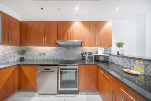 a kitchen with wooden cabinets and stainless steel appliances at Modern 1 Bed in Central Park Sleeps 2 with Pool in Dubai
