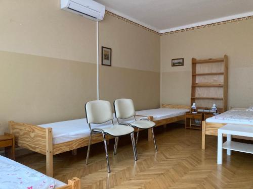 a hospital room with two beds and two chairs at Kurca-parti Vendégház in Szentes