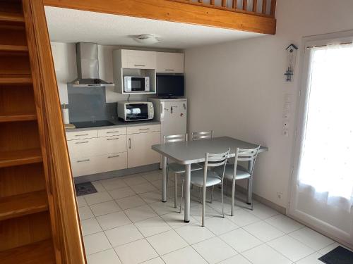 une cuisine avec une table, des chaises et un réfrigérateur dans l'établissement Maisonnette avec Piscine, Terrasse et Jardin Privé - La Faute-sur-Mer - FR-1-194-282, à La Faute-sur-Mer