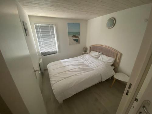 une petite chambre avec un lit blanc et une fenêtre dans l'établissement Maisonnette avec Piscine, Terrasse et Jardin Privé - La Faute-sur-Mer - FR-1-194-282, à La Faute-sur-Mer