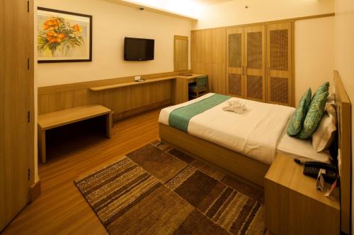 um quarto de hotel com uma cama e uma televisão em Sinclairs Siliguri em Siliguri
