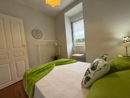 a bedroom with a bed with green sheets and a window at Casa da Avó Quina - Seixas in Coura