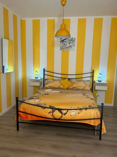 a bed in a room with yellow and white stripes at IL PARADISO delle farfalle in Santa Maria degli Angeli