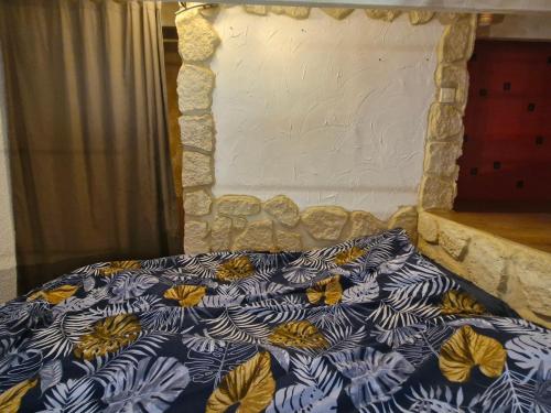 - un lit avec une couette bleue et blanche et un mur en pierre dans l'établissement Appartement 2 pièces avec clim, parking, proche commerces et plage - Sainte-Maxime, Golfe de St-Tropez - FR-1-780-76, à Sainte-Maxime