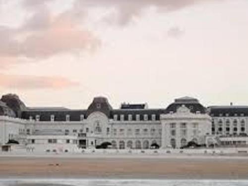 un grand bâtiment blanc avec beaucoup de fenêtres dans l'établissement Studio avec jardin, terrasse et parking à Trouville - FR-1-712-34, à Trouville-sur-Mer