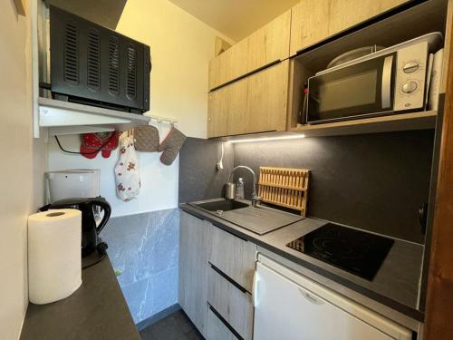 une petite cuisine avec un évier et un micro-ondes dans l'établissement Studio cosy rez de chaussée 4 pers. près des pistes, équipé avec terrasse et parking. - FR-1-733-84, à Crest-Voland
