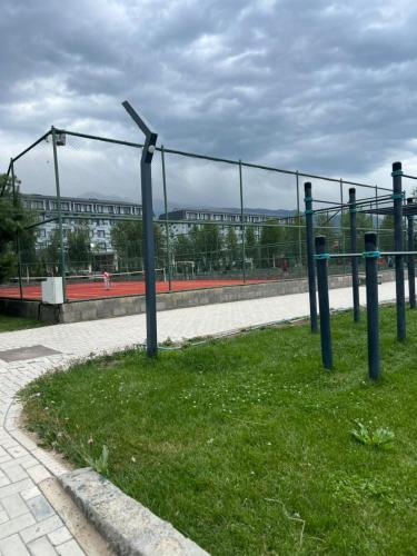 a fence with a tennis court in front of a building at Апартамент,Новел отель,село Корумду in Korumdy