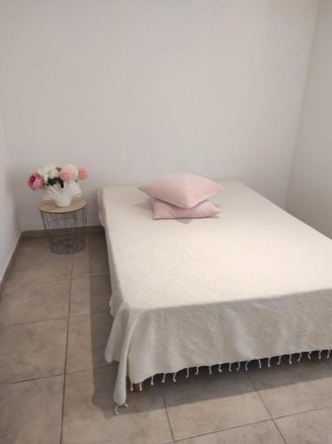 a white bed with pink pillows and a table with flowers at Villa Entre Terre & Mer in Vidauban