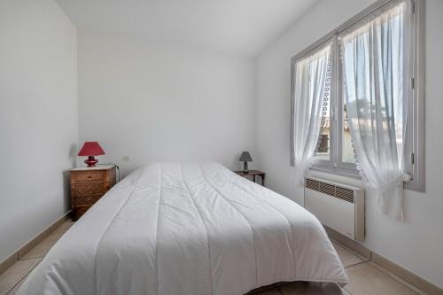ein weißes Schlafzimmer mit einem Bett und einem Fenster in der Unterkunft 600 m de la plage, maison pour 4 adultes 2 enfants in Tharon-Plage