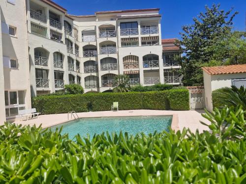 un immeuble avec piscine en face d'un immeuble dans l'établissement Charmant studio à Sainte-Maxime avec piscine, balcon et parking, proche commerces et plages. - FR-1-780-80, à Sainte-Maxime