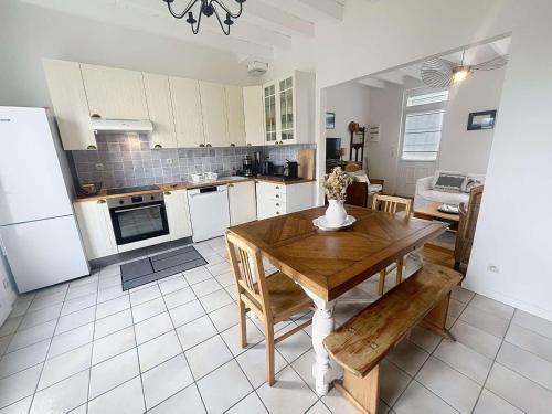 une cuisine avec une table en bois et une salle à manger dans l'établissement Villa au Calme avec Jardin, Proche Plage et Commerces, Wifi et Équipements Complets - FR-1-361-117, à Jullouville