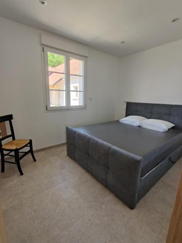 a bedroom with a large bed and a chair at gites des polders in Saint-Quentin-en-Tourmont