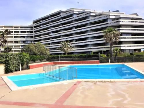 une piscine vide en face d'un grand bâtiment dans l'établissement Appartement 2 pièces avec piscine et parking, accès direct plage - FR-1-748-27, à Canet