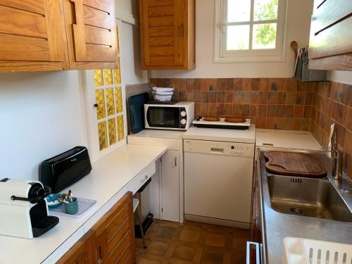 une petite cuisine avec un évier et un micro-ondes dans l'établissement Villa avec Jardin à Cabourg, Proche Plage et Centre - FR-1-487-324, à Cabourg