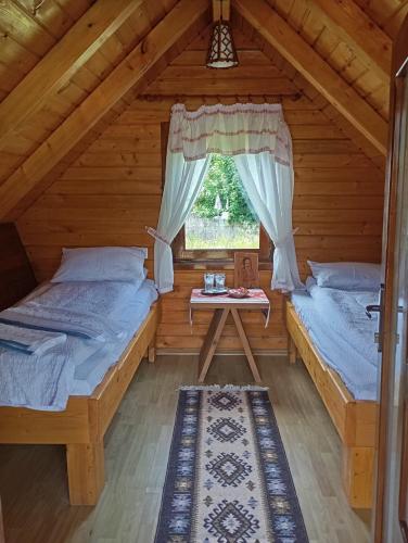 two beds in a log cabin with a window at Cazare la Munte cu Piscină in Bistra