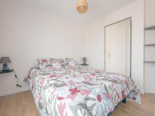 une chambre blanche avec un lit avec un couvre-lit fleuri dans l'établissement Appartement 1 chambre, balcon et accès direct à la plage - FR-1-197-596, à Les Sables-dʼOlonne