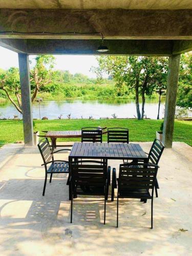 a table and chairs under a pavilion with a lake at Na Khwae Villa Riverside in Nong Bua