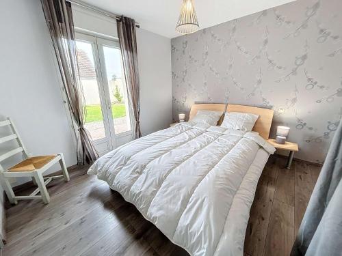 une chambre avec un grand lit blanc et une chaise dans l'établissement Maison à 500m de la plage avec jardin, 4 chambres, Wi-Fi et parking - 8 couchages - FR-1-361-539, à Saint-Pair-sur-Mer