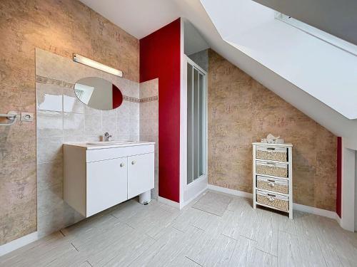 La salle de bains est pourvue d'un lavabo et d'un mur rouge. dans l'établissement Maison à 500m de la plage avec jardin, 4 chambres, Wi-Fi et parking - 8 couchages - FR-1-361-539, à Saint-Pair-sur-Mer