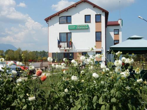 a building with a field of flowers in front of it at Pensiunea Cetatea Craiului in Râşnov