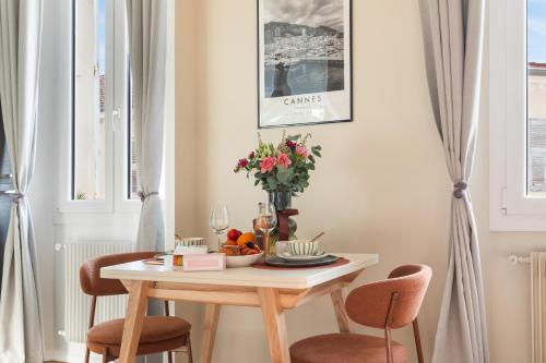 a table with chairs and a vase of flowers on it at Suite design - 3 min Palais & Croisette - Central in Cannes