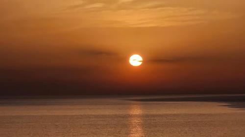 a sunset over the ocean with the sun in the sky at Buggerru Sunset Home in Buggerru