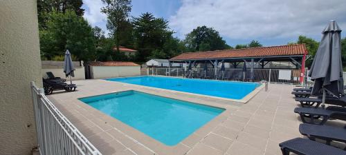 une grande piscine avec chaises et parasols dans l'établissement Mobil home Saint Georges de Didonne, à Saint-Georges-de-Didonne