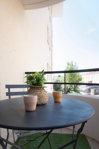 a blue table with two plants on a balcony at Appart Romarin - Proche Gare & Stadium in Miramas
