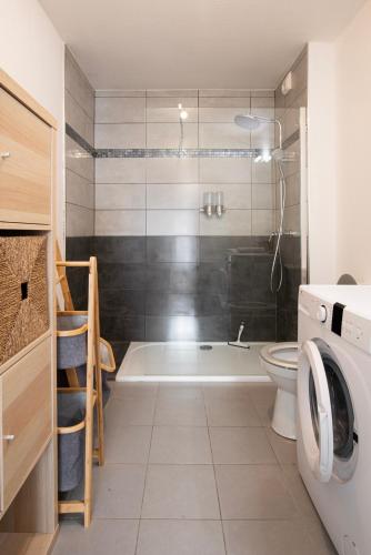 a bathroom with a tub and a toilet and a washing machine at Appart Romarin - Proche Gare & Stadium in Miramas