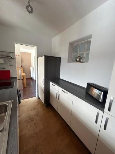 a kitchen with white cabinets and a black counter top at Zur Mühle in Varel