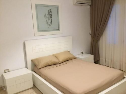 Un dormitorio blanco con una cama y una ventana. en Romance d'été, en Hammam Sousse