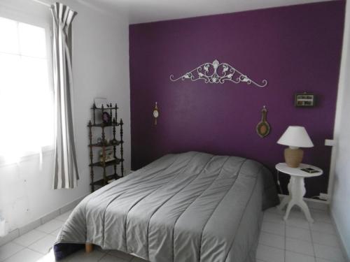 - une chambre avec un lit et un mur violet dans l'établissement Maison calme proche plage Noirmoutier, 6 personnes, animaux admis, parking privé - FR-1-823-76, à Noirmoutier-en-l'lle