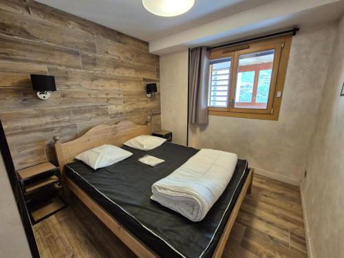 a bedroom with a bed with a wooden wall at Bel appartement moderne 8 pers, 250m des pistes - FR-1-811-24 in Les Deux Alpes