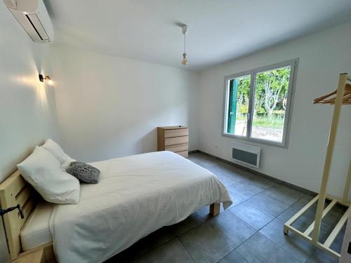 a white bedroom with a bed and a window at Parenthèse à la Maison de Gilda in Eygalières