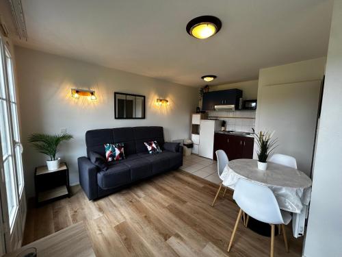 un salon avec un canapé noir et une table dans l'établissement T2 avec Piscine Commune et WIFI à 200m des Thermes - FR-1-541-151, à La Roche-Posay